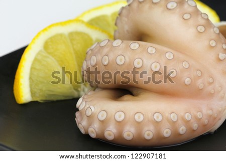 Raw octopus tentacles ready to be cooked with slices of lemon