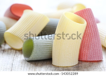Italian cuisine concept - tri coloured tortiglioni pasta representing Italian flag on a rustic wooden background