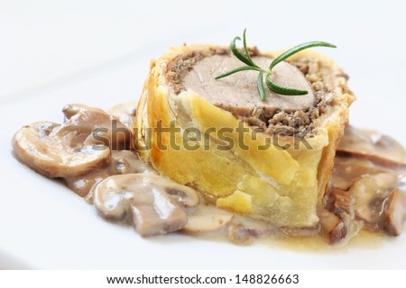 Slice of Pork Wellington with mushroom sauce - tenderloin coated in mushroom pate, duxelles and Parma ham and wrapped in puff pastry