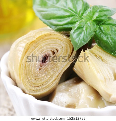 Artichoke hearts appetizer topped with a fresh leaf of green basil