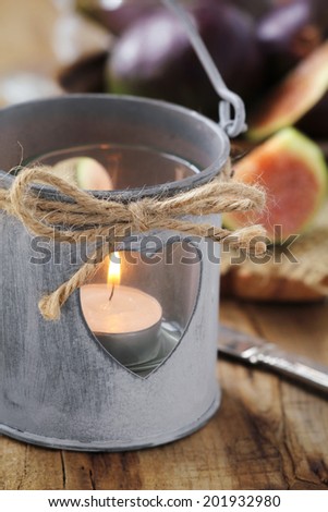 Cozy outdoor dinner - Romantic shabby chic style lantern with a lit tealight candle and fresh figs at the background