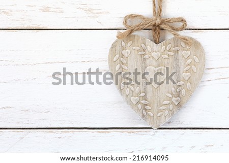 Shabby chic heart shaped ornament on a jute twine with a bow against white wooden background with copy space