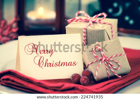 Textured greeting card with copy space for your own text on a plate with wrapped Christmas presents as a concept of a festive dinner with retro vintage filter effect