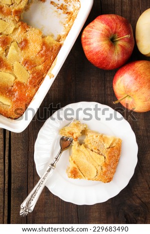 Piece of homemade Charlotte pie made of Gala apples served on a white plate with a fork
