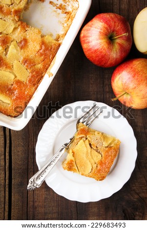 Piece of homemade Charlotte pie made of Gala apples served on a white plate with a fork