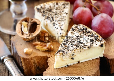 Brie or Camembert like cheese with ground black pepper - traditional French Pithivier aux poivre cheese with white mold