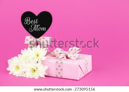 Happy mother\'s day greeting card with a pink gift, chrysanthemum flowers and a heart shaped tag with Best Mom message with plenty of copy space