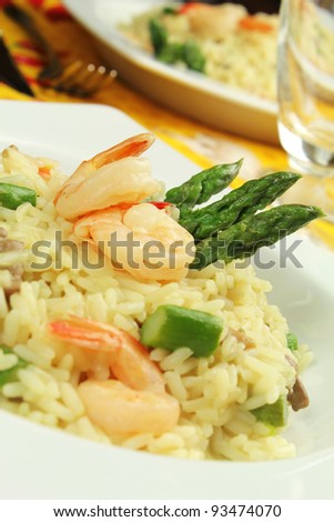 Delicious italian risotto with asparagus, shrimps and champignon mushrooms served on a white rectangle plate