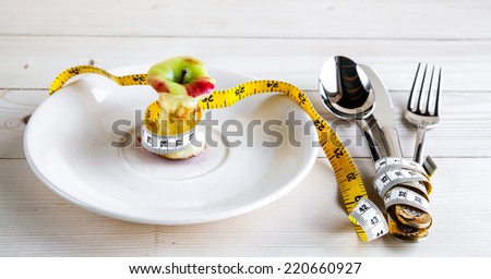 plate with stub, measure tape, knife and fork. Diet food on wooden table