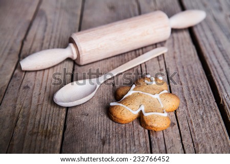 Rolling pin and homemade gingerbread men biscuits on a wooden board with flour