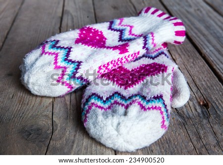 Classic knitted set of mittens and hats on the old wooden background