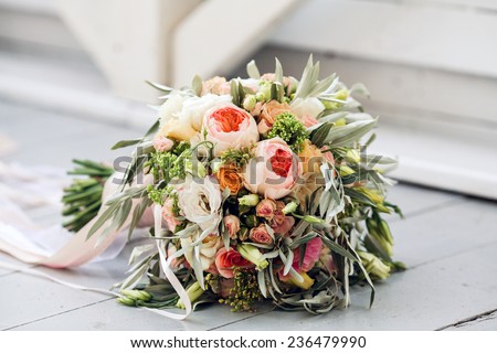 Beautiful bridal bouquet tied with silk ribbons and lace with a key in the form of heart. Roses and branches of an olive tree on the old vintage background . Wedding Accessories
