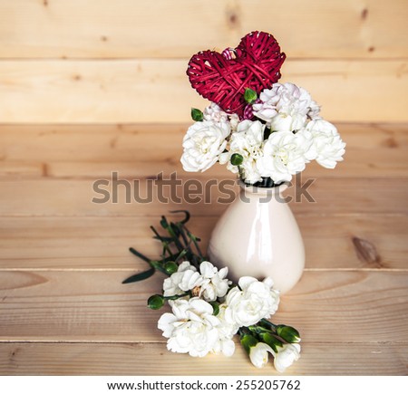 flowers. delicate bouquet of carnations in vintage vase with heart on wooden background. Valentine's Day