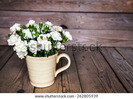 delicate bouquet of carnations in vintage vase with heart on wooden background. Valentine's Day