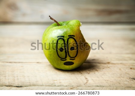 green apple with a hole bitten into it on a brown wooden surface