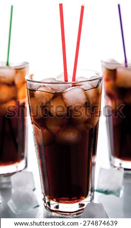 three glasses of cola with ice and straws on a white background. soft drinks