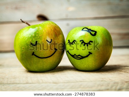 Face on a green apple. Couple in love. Wooden background