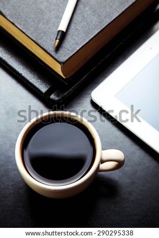 empty tablet pc and a coffee and notebook with pen on the office desk