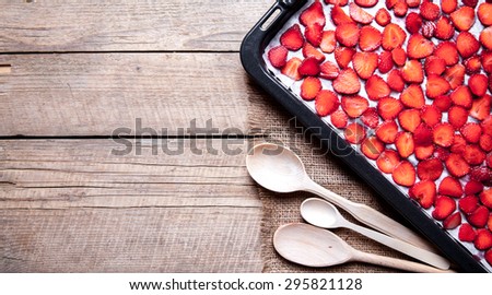fruit. sliced Strawberry with wooden spoons baking on a dark metal plate in oven. wood background