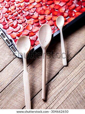 fruit. sliced Strawberry with wooden spoons baking on a dark metal plate in oven. wood background