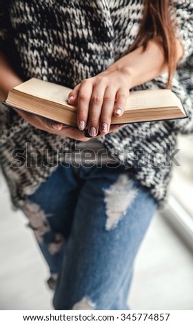 happy female student holding a book in torn jeans