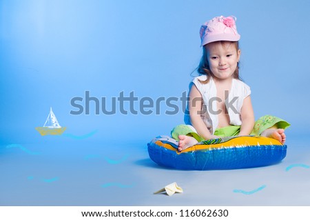Portrait of funny little girl fishing in a studio and looking at a drawn fish
