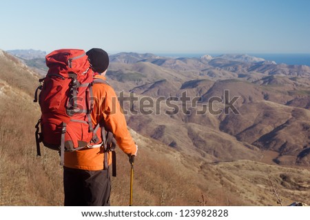Hiking man with backpack and hiking poles looking at beautiful scenery