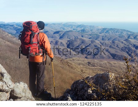 Hiking man with backpack and hiking poles looking at beautiful scenery, view of the Crimean mountains, Ukraine