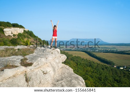 Smiling young woman standing on the top of mountain