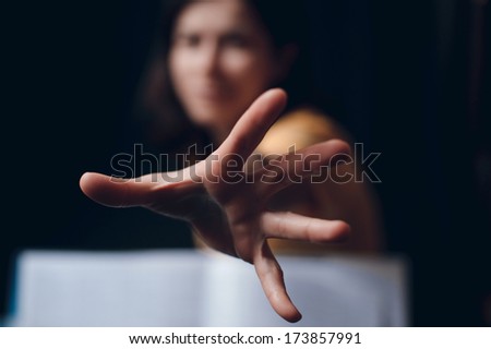 Hand protruding out from an open book, focus on fingers, reading concept