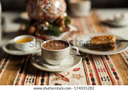 A cup of coffee on the traditional turkish tablecloth with honey and baklava, cup in the focus