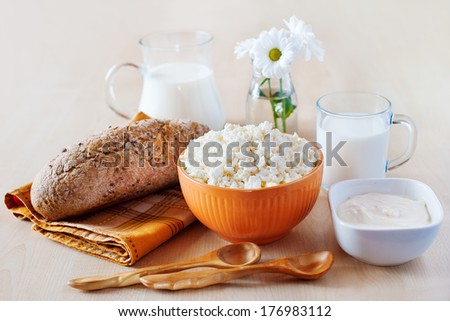 Group of dairy products: cottage cheese, milk, sour cream and bread on white wooden table