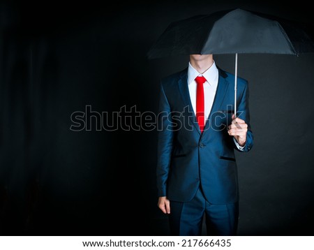 Portrait of businessman wearing dark suit and red tie holding an umbrella