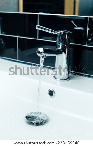 Water tap with flowing water in the bathroom