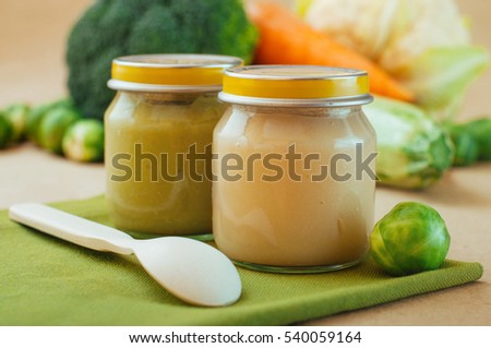 Glass jars with natural baby food on the table: vegetable puree with Brussels sprouts, squash, broccoli, cauliflower; selective focus