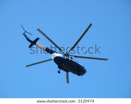The helicopter flying against the blue sky
