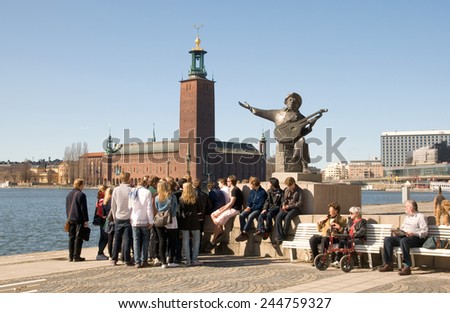 STOCKHOLM, SWEDEN - APRIL 14, 2010: A group of young people near the Evert Taube monument. In the background is the Town Hall. Evert Taube was  a Swedish author, artist, composer and singer