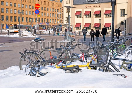 HELSINKI, FINLAND - MARCH 13, 2010: The bikes under the snow near Central Railway Station. On the background is Vltava Restaurant. Left - Central Post Office