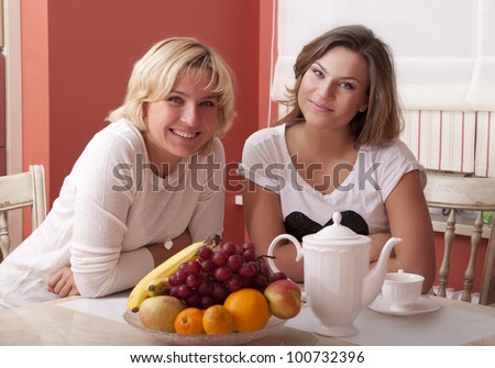 Happy smiling mother and daughter have breakfast. Looking at camera