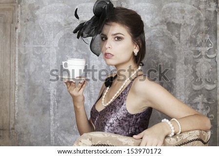 Beautiful young pin-up girl dressed up in retro clothing drinking tea
