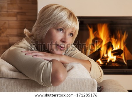 Daydreaming Caucasian woman sitting on sofa at home by fireplace