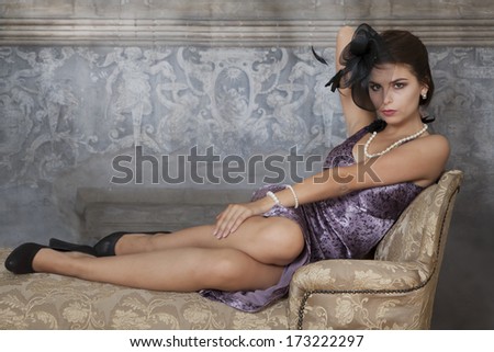 Beauty brunette model on antique couch from Victorian era
