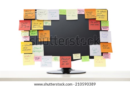 Various note papers on computer monitor, on white background