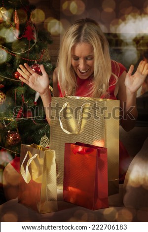 Ecstatic young woman enjoying at Christmas, she is opening gifts and surprisingly looking what is inside