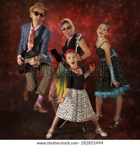 Rock musician family have fun playing music and singing on a black background with glowing lights