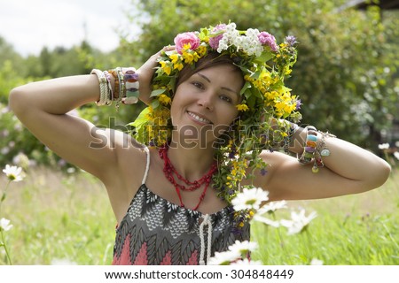 Romantic girl in a wreath of wild flowers looking at the camera. Summer. Hippie style.
