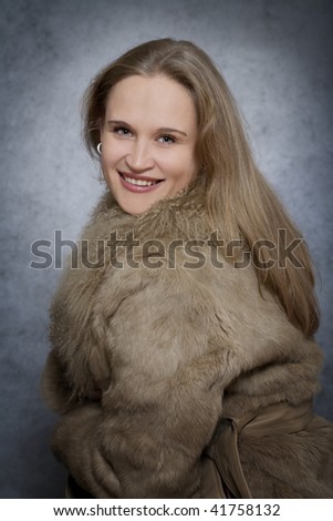 Portrait of  woman dressed in fur coat over grey background