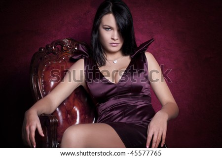 Portrait of an elegantly beautiful young woman posing on an antique chair