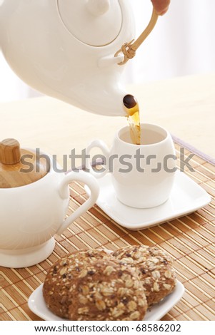 Someone is pouring a tea into a cup during breakfast