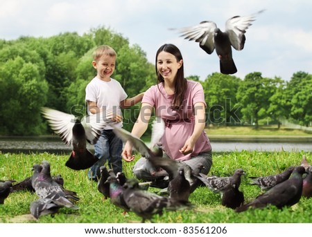 Pregnant woman with her son feeding pigeons in a park